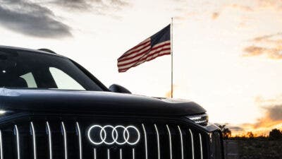 Frontale Audi nera con bandiera americana al tramonto