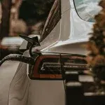 Auto elettrica bianca in ricarica su strada