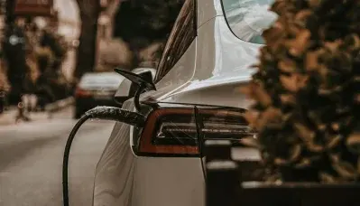 Auto elettrica bianca in ricarica su strada