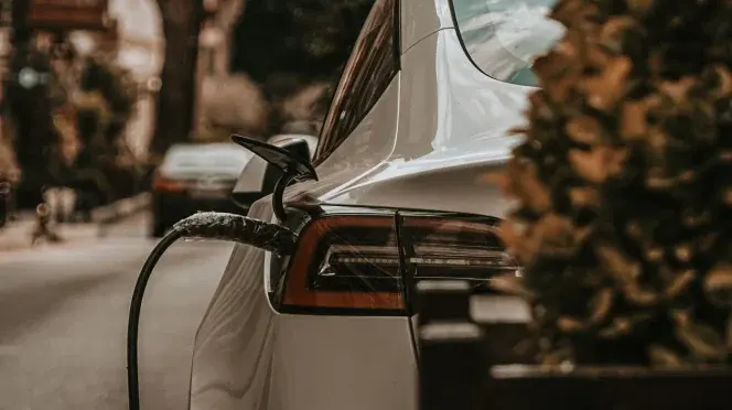 Auto elettrica bianca in ricarica su strada
