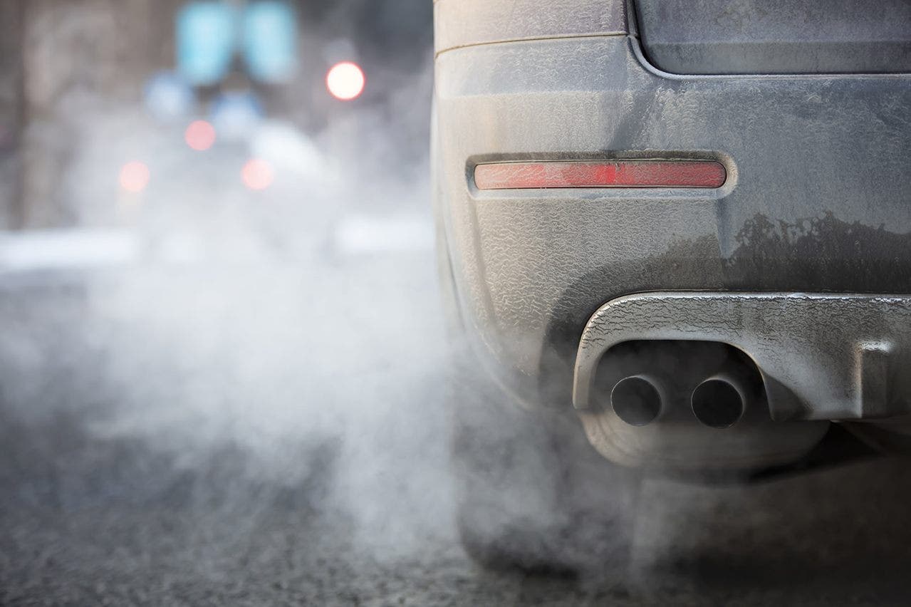 Scarico auto emette fumo in una strada trafficata
