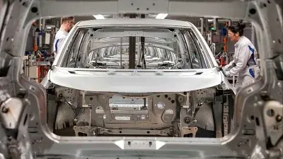 Operai assemblano scocche automobilistiche in una fabbrica