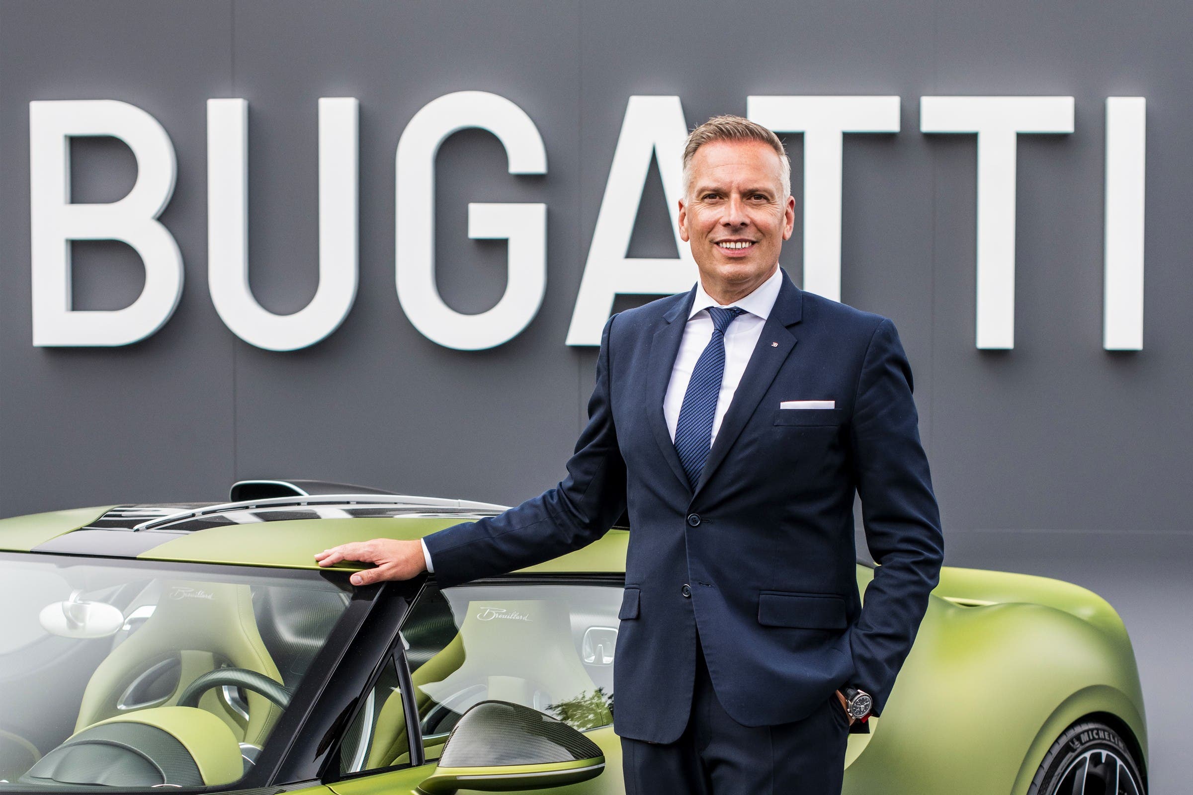 Dirigente Bugatti accanto a una supercar verde