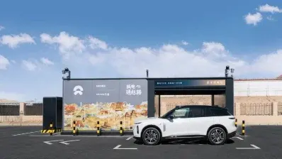 SUV elettrico bianco davanti a stazione di scambio batterie NIO