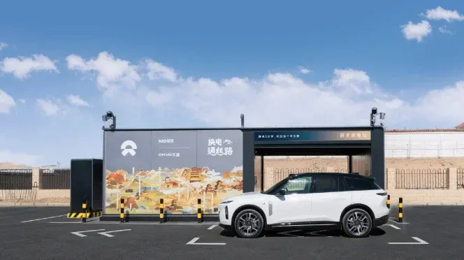 SUV elettrico bianco davanti a stazione di scambio batterie NIO