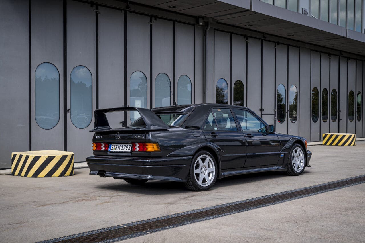 Mercedes-Benz 190E nera parcheggiata davanti a edificio moderno