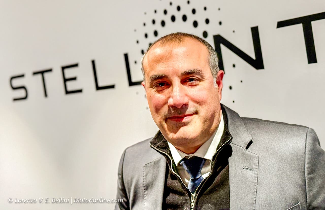 Emanuele Cappellano in un’intervista durante un evento automobilistico, con sfondo sfocato e abbigliamento formale